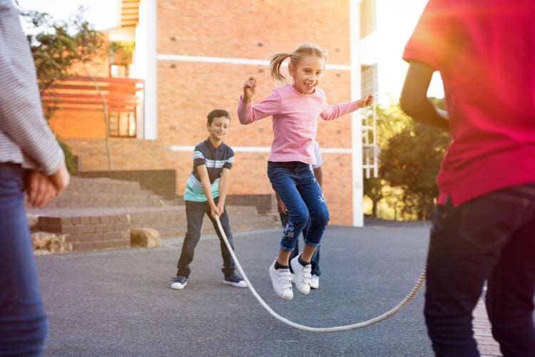 Kinderen buiten spelen op straat - springtouw
